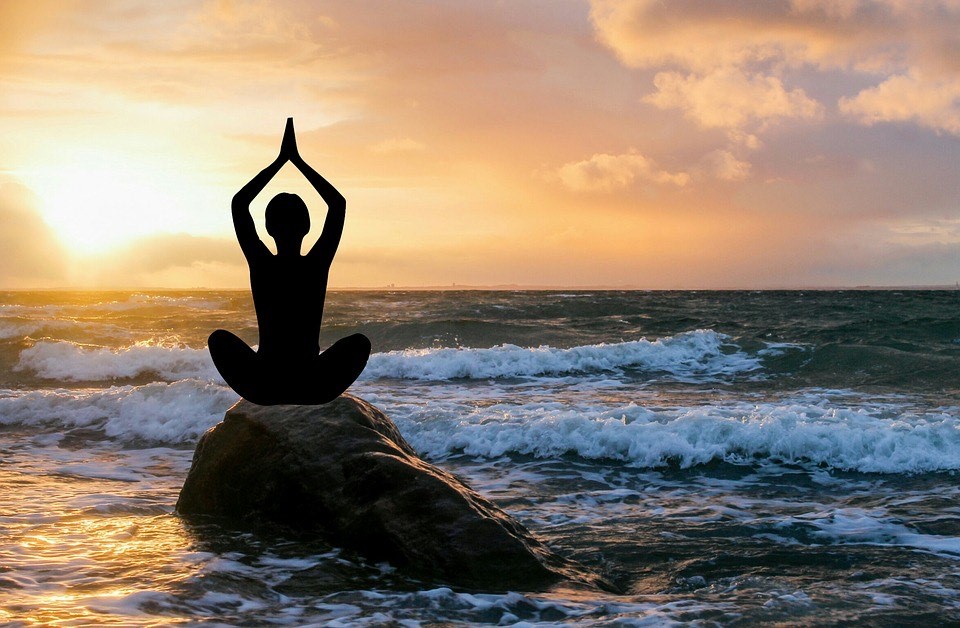 A person sitting on top of a rock in the ocean.