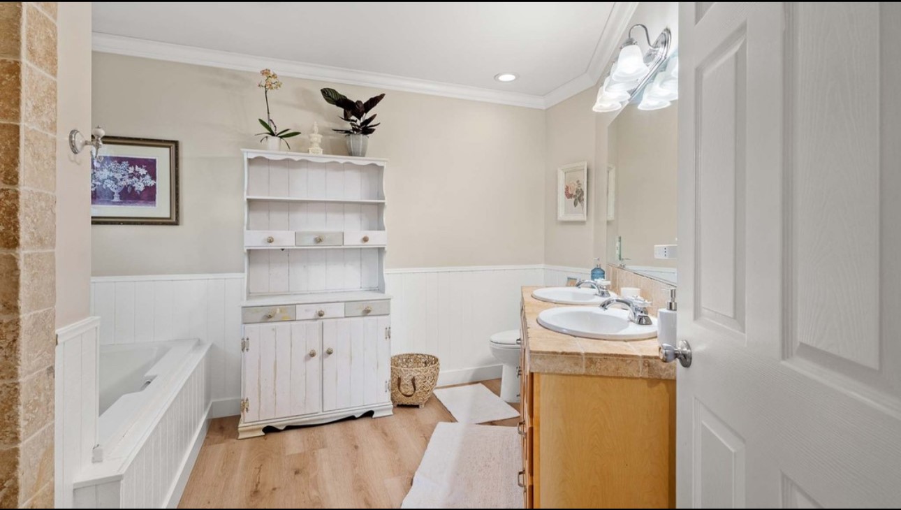 A bathroom with wood floors and white walls.