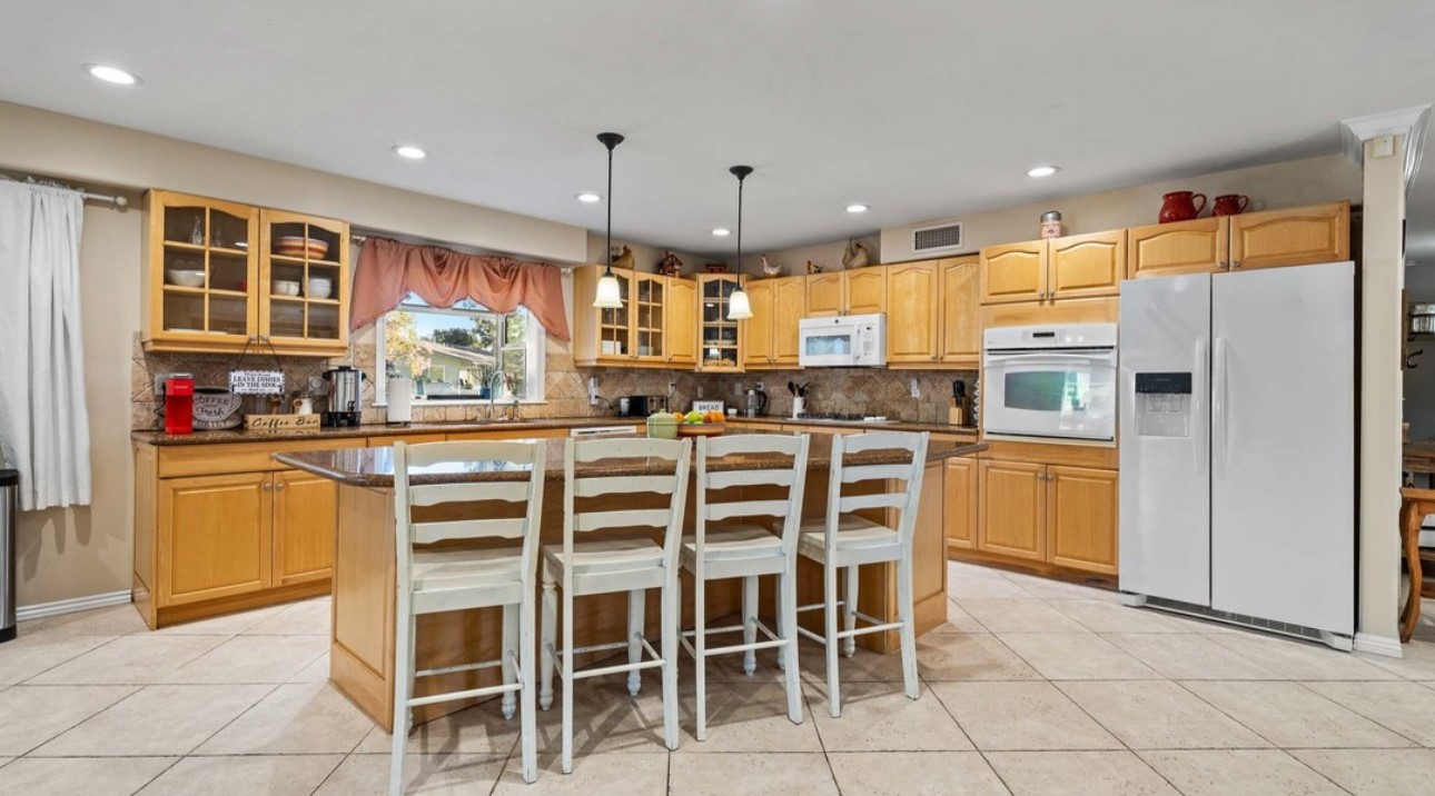 A kitchen with wooden cabinets and white tile floors.