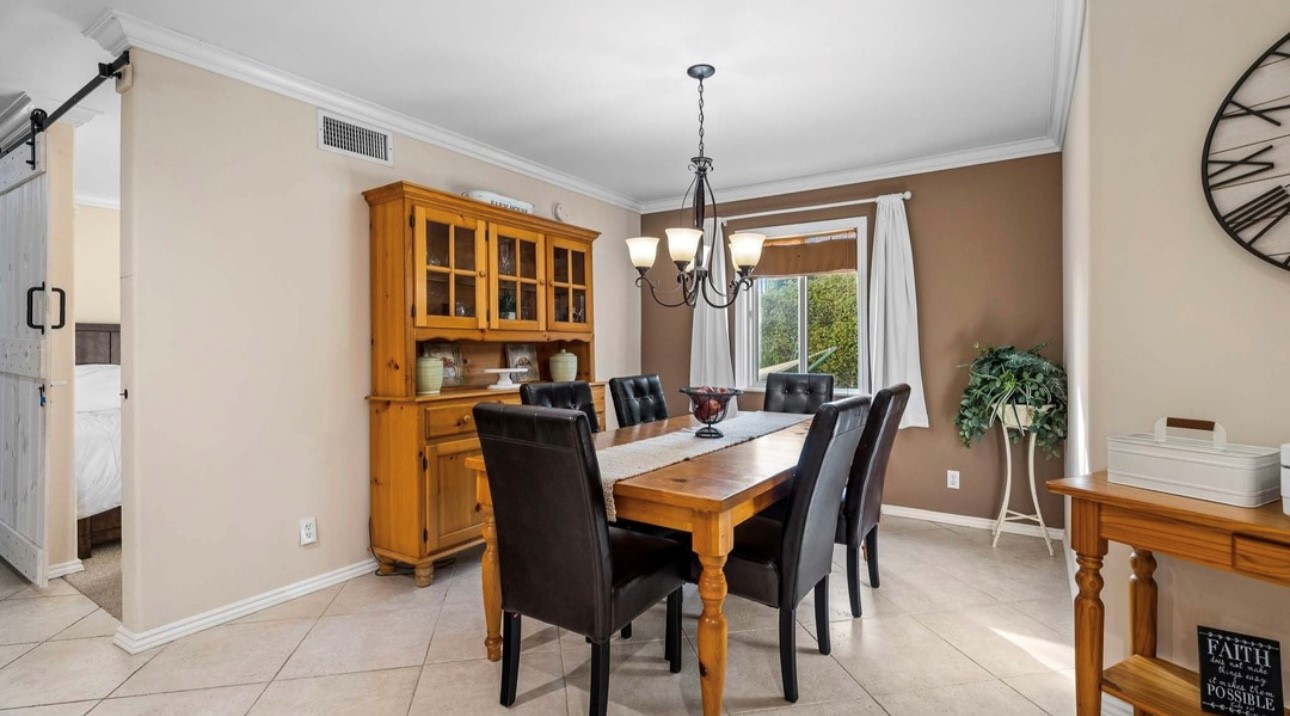 A dining room table and chairs in front of a wooden cabinet.