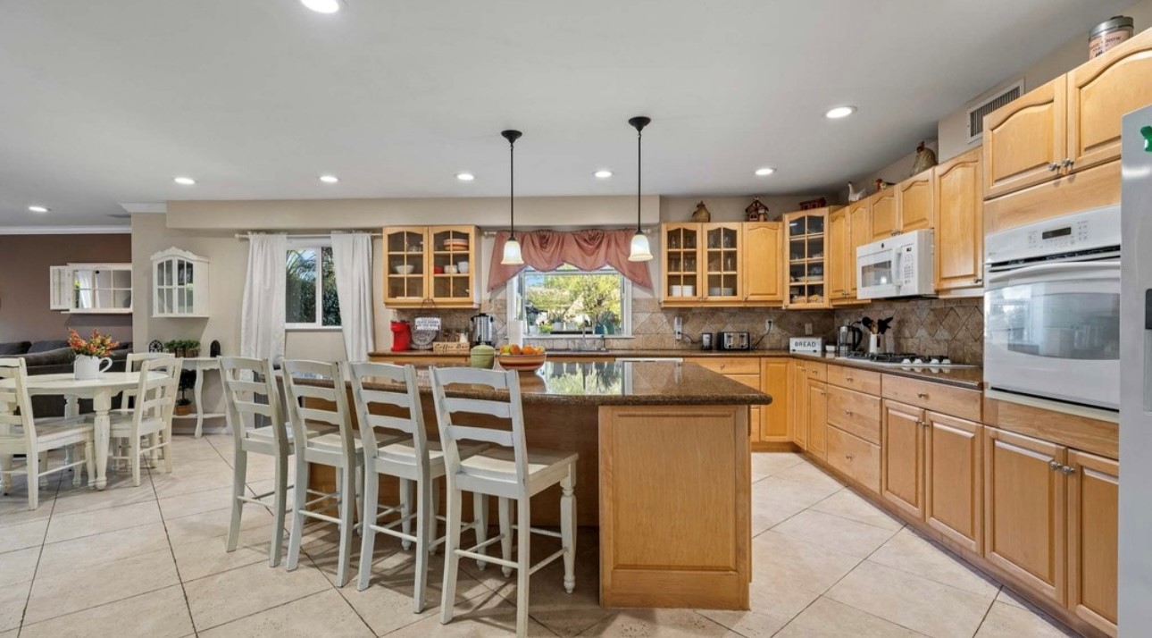 A kitchen with wooden cabinets and white chairs