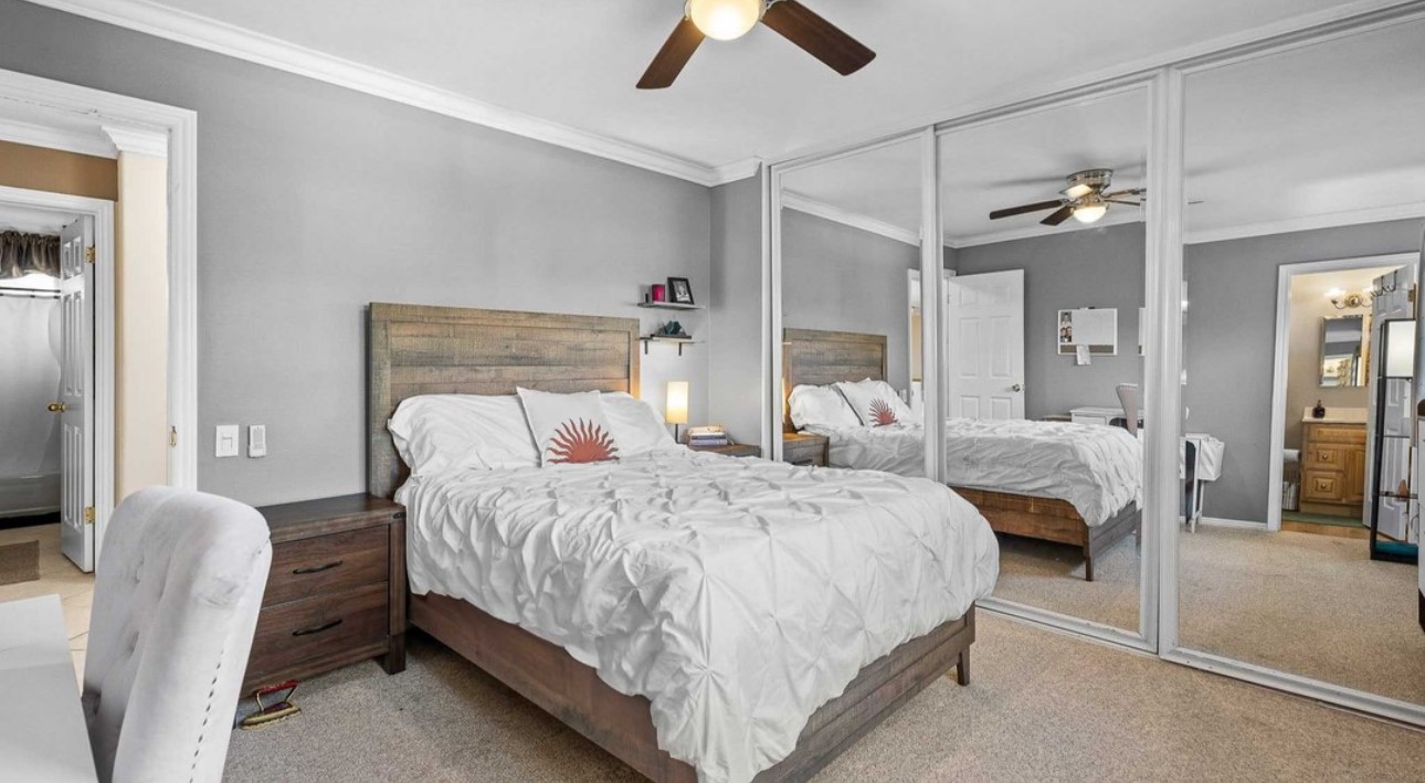 A bedroom with a bed, dresser and mirror.