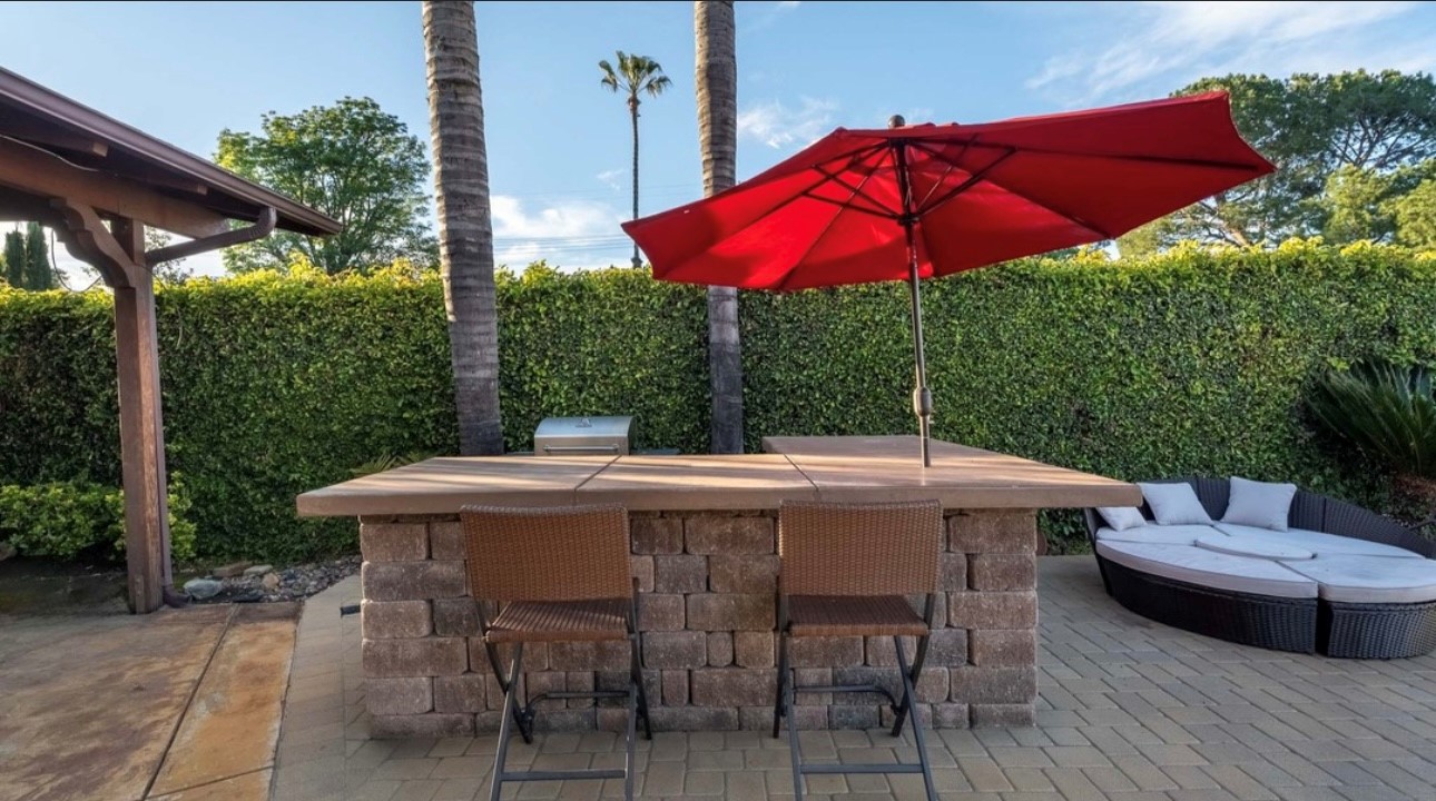 A red umbrella is on the patio next to an outdoor bar.