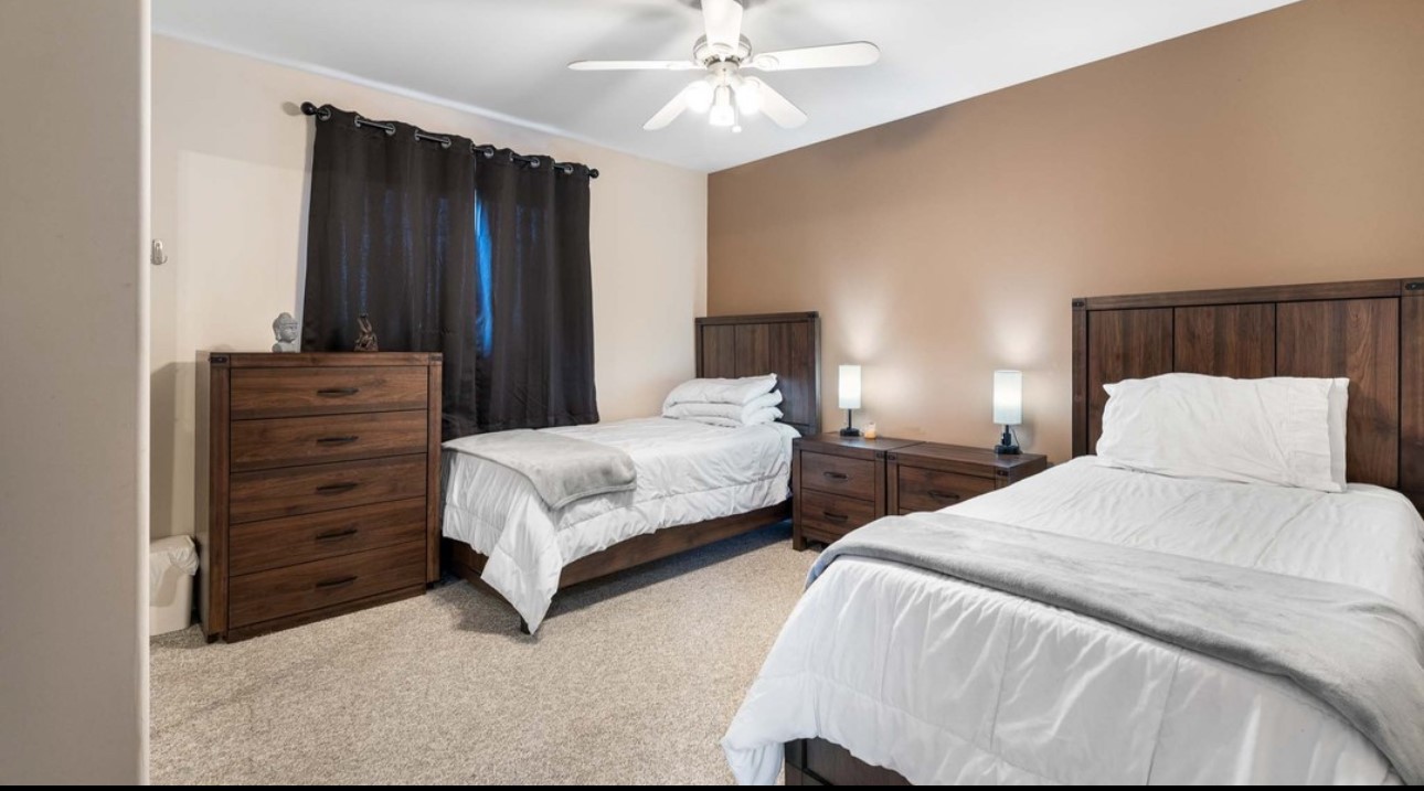 A bedroom with two beds and a dresser.