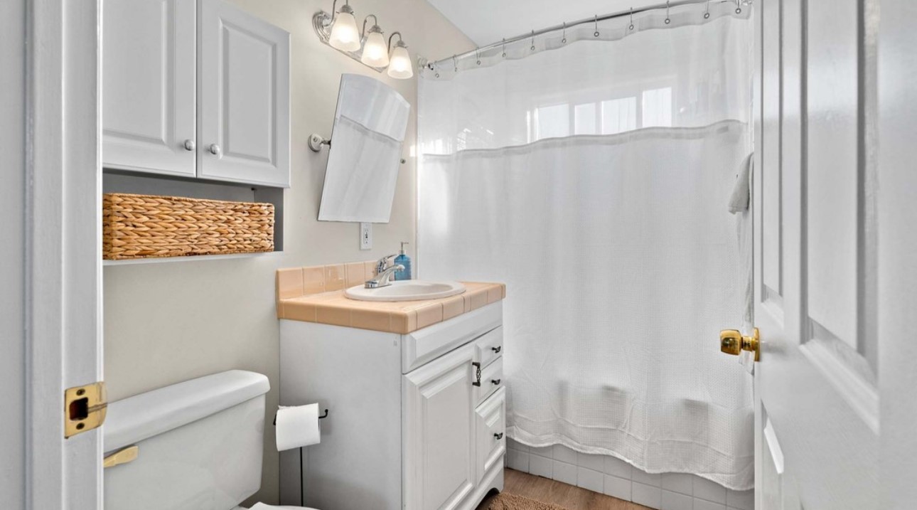 A bathroom with white walls and wooden floors.