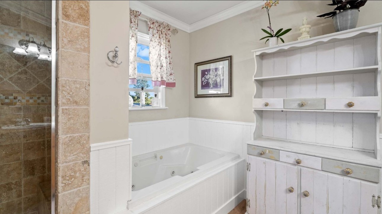 A bathroom with white walls and wooden floors.