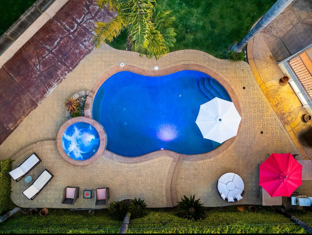 A pool with an umbrella and chairs in the middle of it