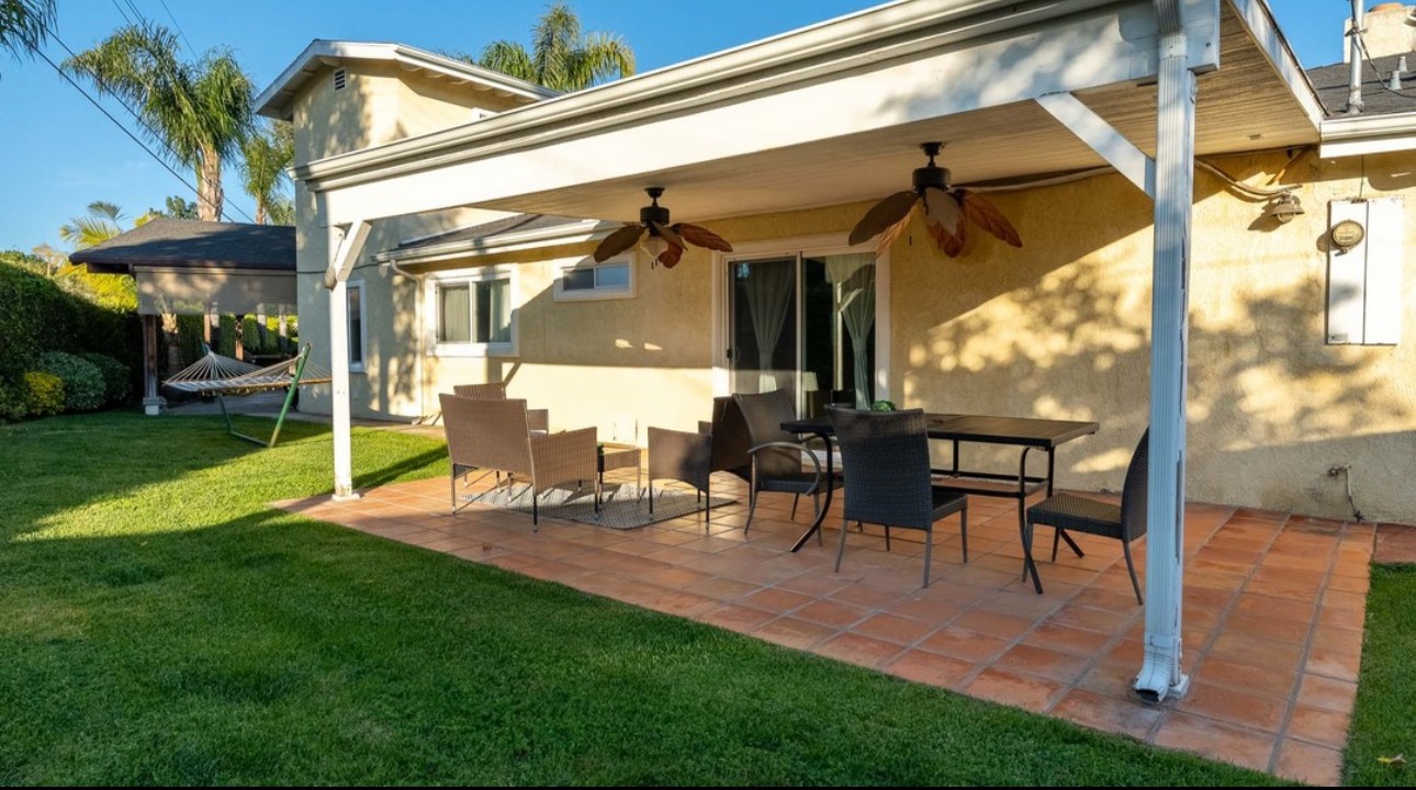 A patio with chairs and tables outside of the house.